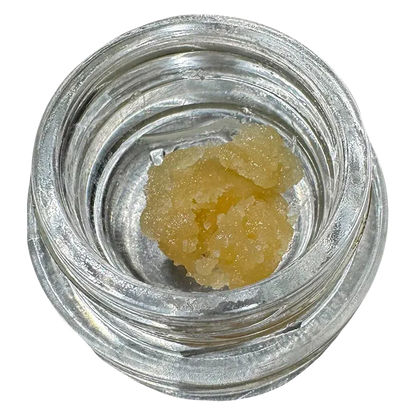 Top-down view of a pale yellow sugar-like concentrate in a small clear jar labeled Turbo Sugar Wax.