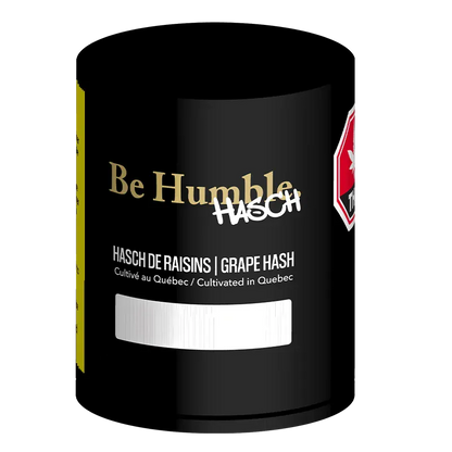 Close-up front view of the black Be Humble Grape Hash canister with gold logo, white "HASCH" graffiti, and product text visible.