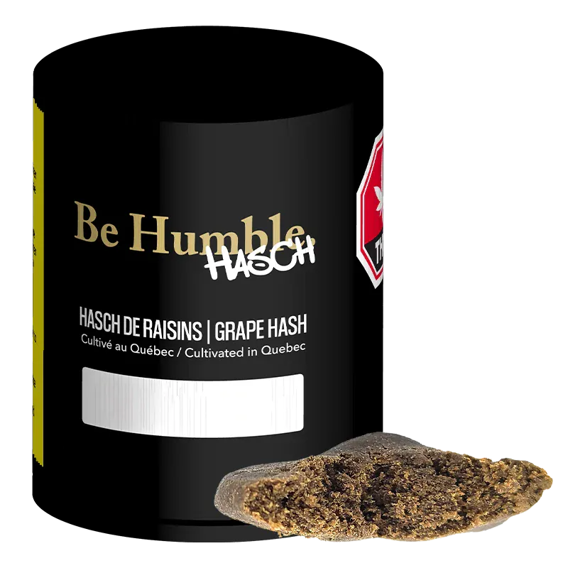 Angled close-up of a black jar labeled "Grape Hash" by Be Humble with a broken brown hash piece resting in front.