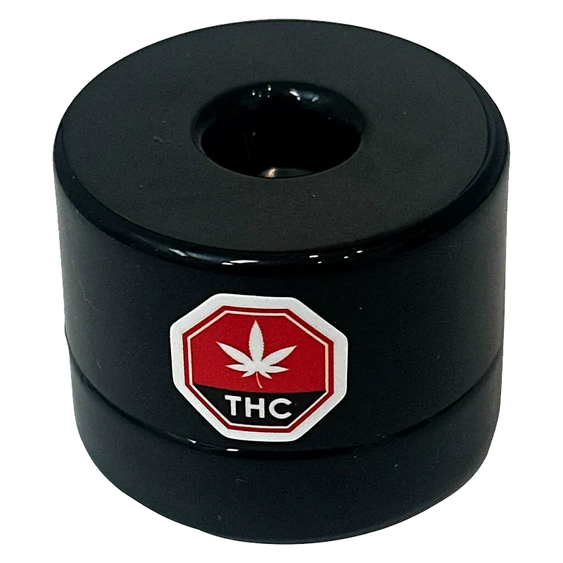 Top-down view of the black Single Source Live Rosin puck with a central depression and a red THC leaf octagon logo on its side