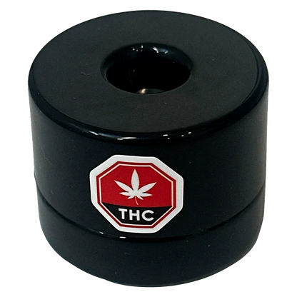 Top-down view of the black Single Source Live Rosin puck with a central depression and a red THC leaf octagon logo on its side