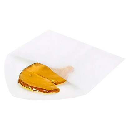 Close-up of a golden amber shard partially wrapped in white parchment labeled Exhaust Haze Shatter.