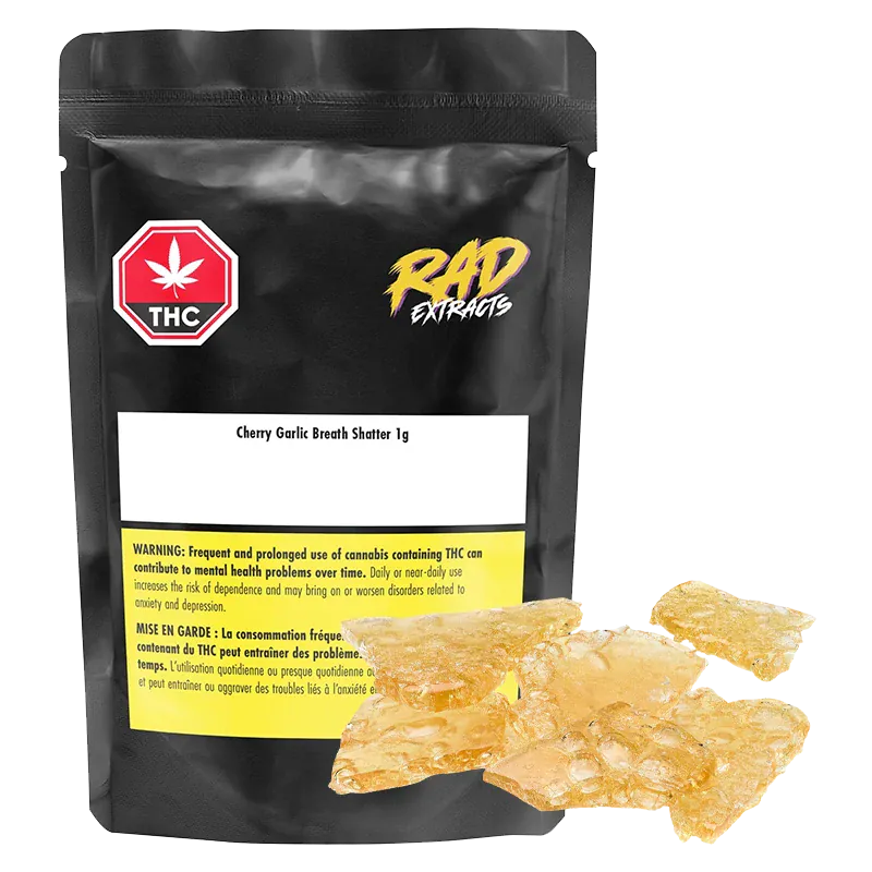 Front-facing shot of a black pouch and amber glassy shards labeled Mango Kush x Galactic Giggles Shatter, the 1 g pieces gleaming against a white background