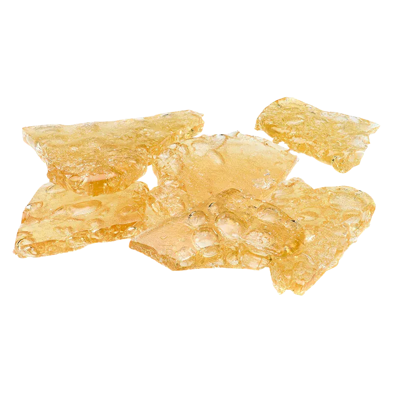 Close-up top-down view of amber, glassy shatter pieces labeled Mango Kush x Galactic Giggles Shatter scattered on a white background