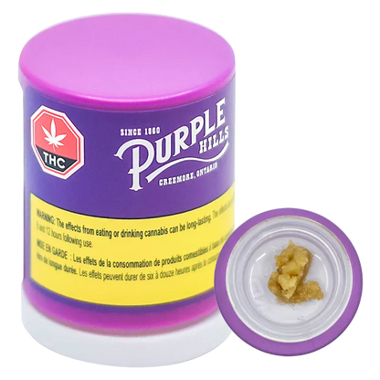 Front-angle photo of a purple container labeled "Purple Hills" with its lid off showing a dab of Tropical Twist Live Resin Badder in a small white dish.