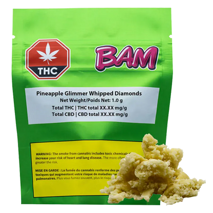 Front-facing shot of a green pouch labeled "Pineapple Glimmer Whipped Diamonds" with a pink "BAM" logo and a crumbly pale concentrate heap in the foreground.