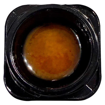 Top-down close-up of a glossy amber concentrate inside its black plastic jar labeled Live Rosin Reserve.