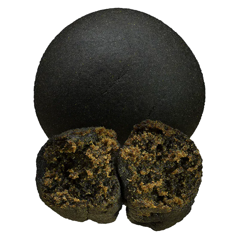 Top-down view of a whole and split round piece of Double Black Hash showing its smooth dark exterior and crumbly golden-brown interior.