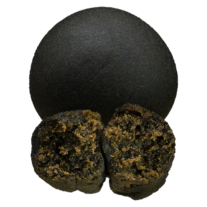 Top-down view of a whole and split round piece of Double Black Hash showing its smooth dark exterior and crumbly golden-brown interior.