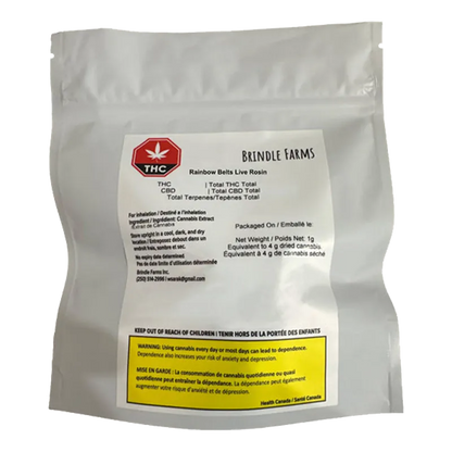 Front-facing photo of a white foil pouch labeled "Brindle Farms Rainbow Belts Live Rosin" with a red THC symbol and a yellow warning box at the bottom