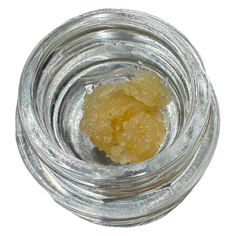 Top-down view of a pale yellow crumble inside a clear glass jar labeled Bane Chamber Wax.