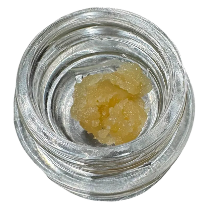 Top-down view of a pale yellow crumble inside a clear glass jar labeled Bane Chamber Wax.