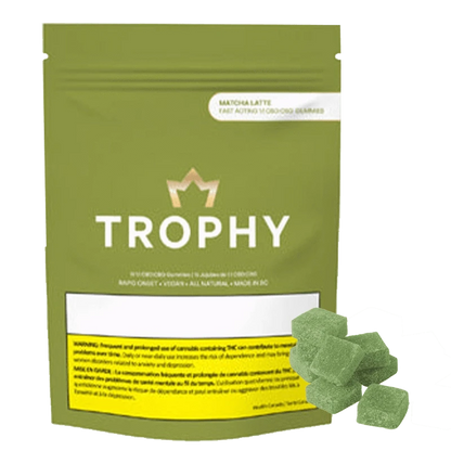 A top-down shot of green Matcha Latte 1:1 CBD:CBG Fast Acting Gummies scattered across a dark surface.