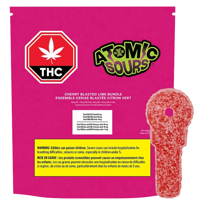 Front-facing bright magenta package labeled "Cherry Blasted Lime Bundle Gummies" with an Atomic Sours logo, THC stop sign, and a red sugar-coated key-shaped gummy alongside.