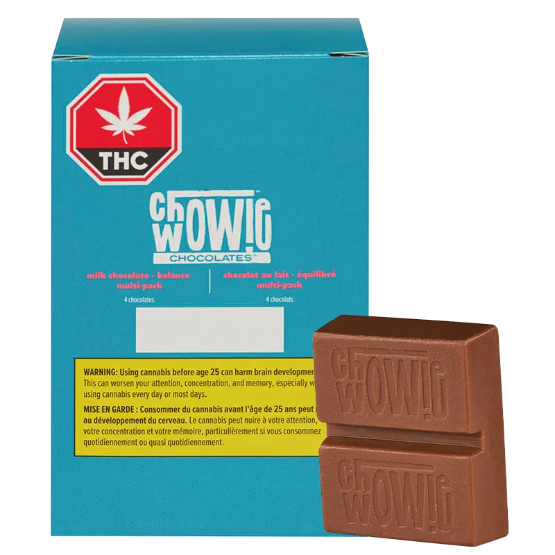 Three-quarter view of a stacked milk chocolate bar in front of a teal box labeled Chwowig Chocolates Balanced Milk Chocolate.