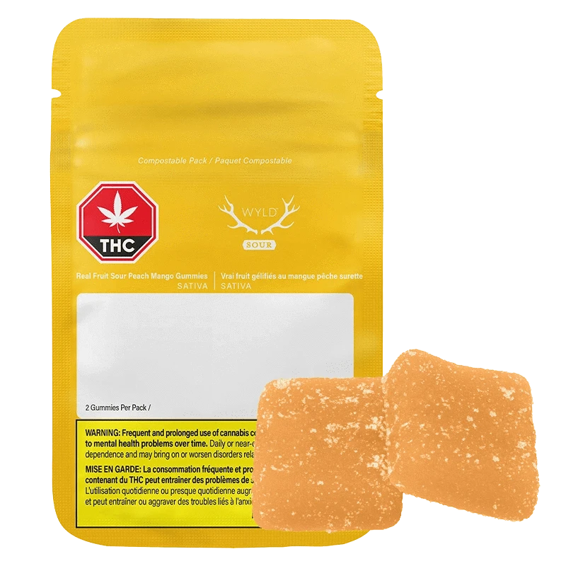Front-facing yellow pouch and two sugar-coated orange squares of Sour Peach Mango 3:1 CBG:THC Gummies.