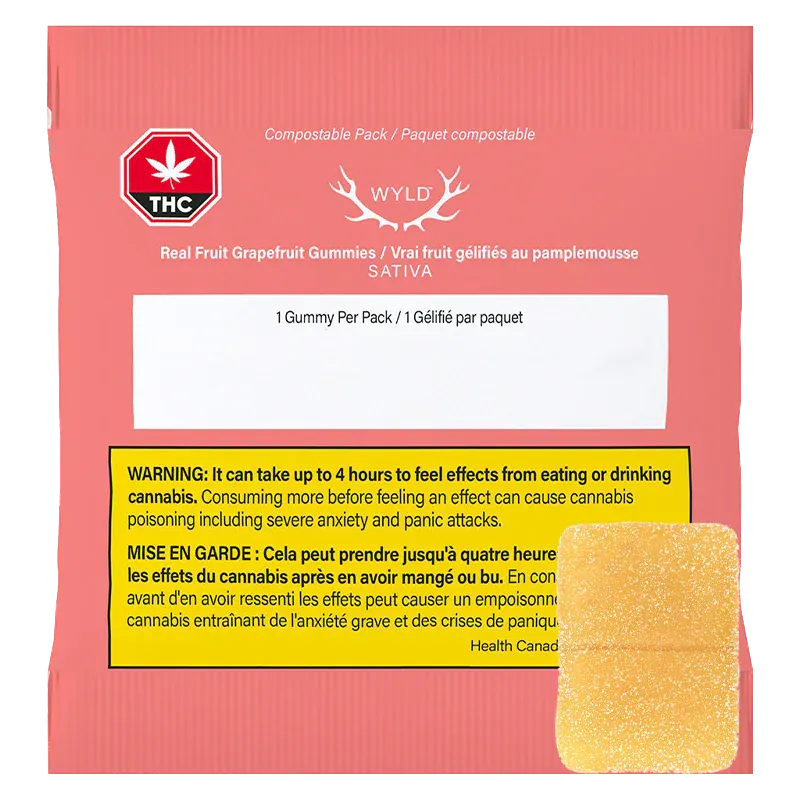 Rear view of the coral packet of Real Fruit Grapefruit Gummies showing a WYLD logo, THC warning badge, yellow bilingual warning box, and a single sugar-coated gummy.