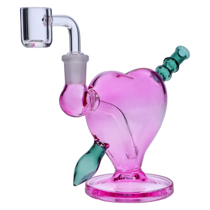 Close-up three-quarter view of the Heart Bong w/Bowl + Banger showing a pink heart-shaped glass body with a green angled mouthpiece and clear quartz banger.