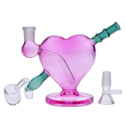 Front view of the pink Heart Bong w/Bowl + Banger heart-shaped glass piece with green angled mouthpiece and bowl shown on a pale background.