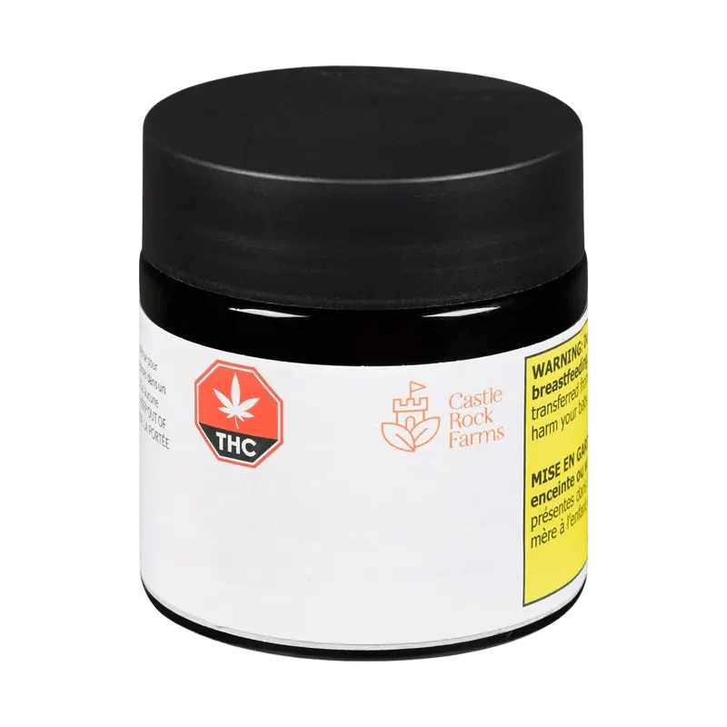 Front three-quarter view of a small jar labeled Pink Grapes by Castle Rock Farms with a black lid, white label, THC icon, and yellow warning patch.