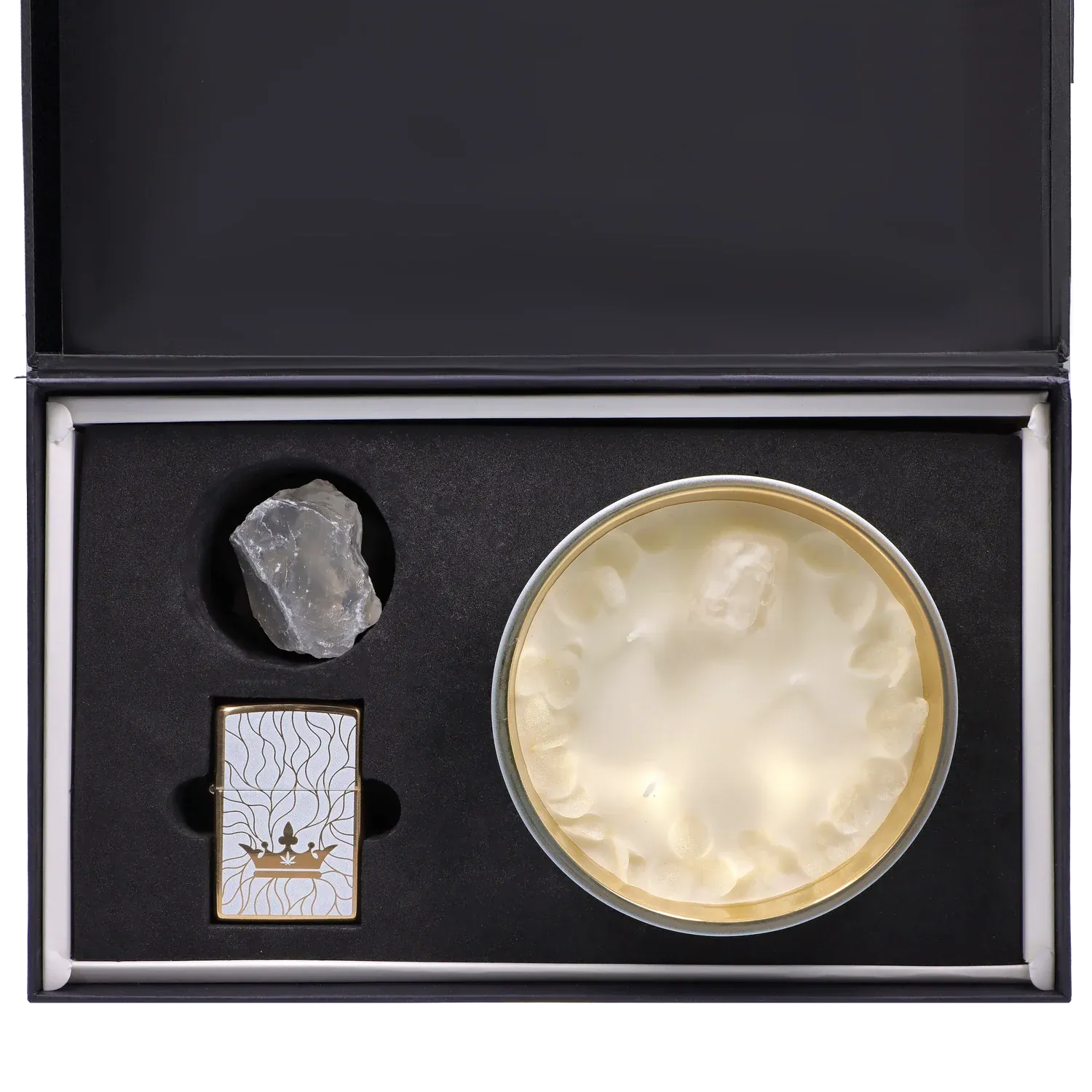 Top-down view of the Queen of Bud: Clarity Ritual Box – Candle, Zippo, and Crystal showing a round white candle in a gold tin, a clear rough crystal, and a patterned gold Zippo nestled in black foam.