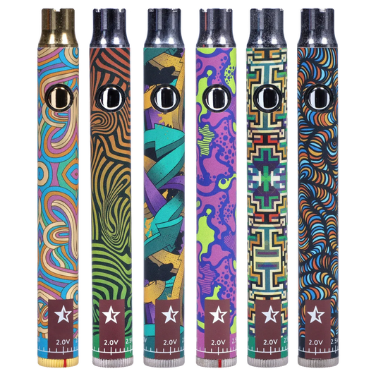 Front-facing close-up of six colorful Famous Design Lit Sticc VV Battery - Mixed Design pens standing upright, each showing a chrome button and distinct psychedelic pattern.