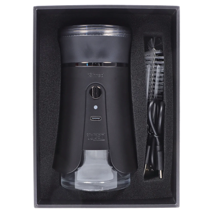 Top-down view of the black Yocan iShred Electronic Grinder – Black nestled in foam packaging with a USB cable and cleaning brush beside it.