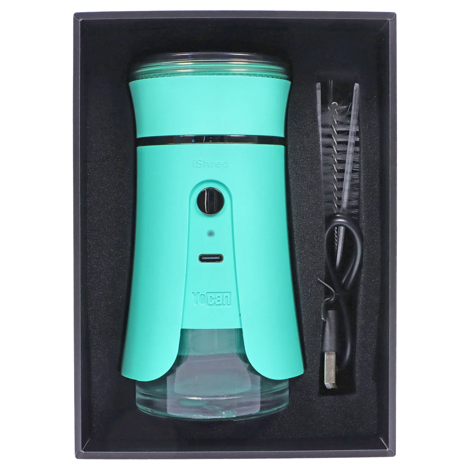 Top-down view of the green Yocan iShred Electronic Grinder seated in black foam packaging with a USB cable and cleaning brush alongside.