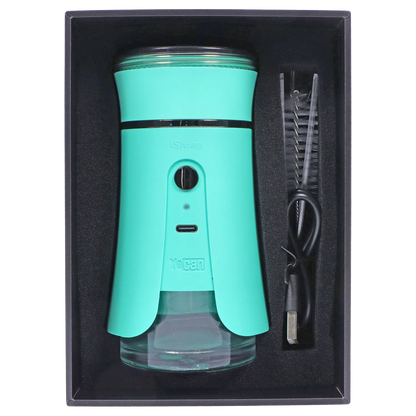 Top-down view of the green Yocan iShred Electronic Grinder seated in black foam packaging with a USB cable and cleaning brush alongside.