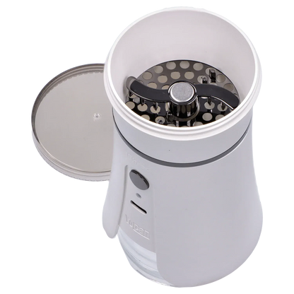 Top-down close-up of the ivory Yocan iShred Electronic Grinder showing its open chamber with a visible two-blade metal grinding plate and removed lid.
