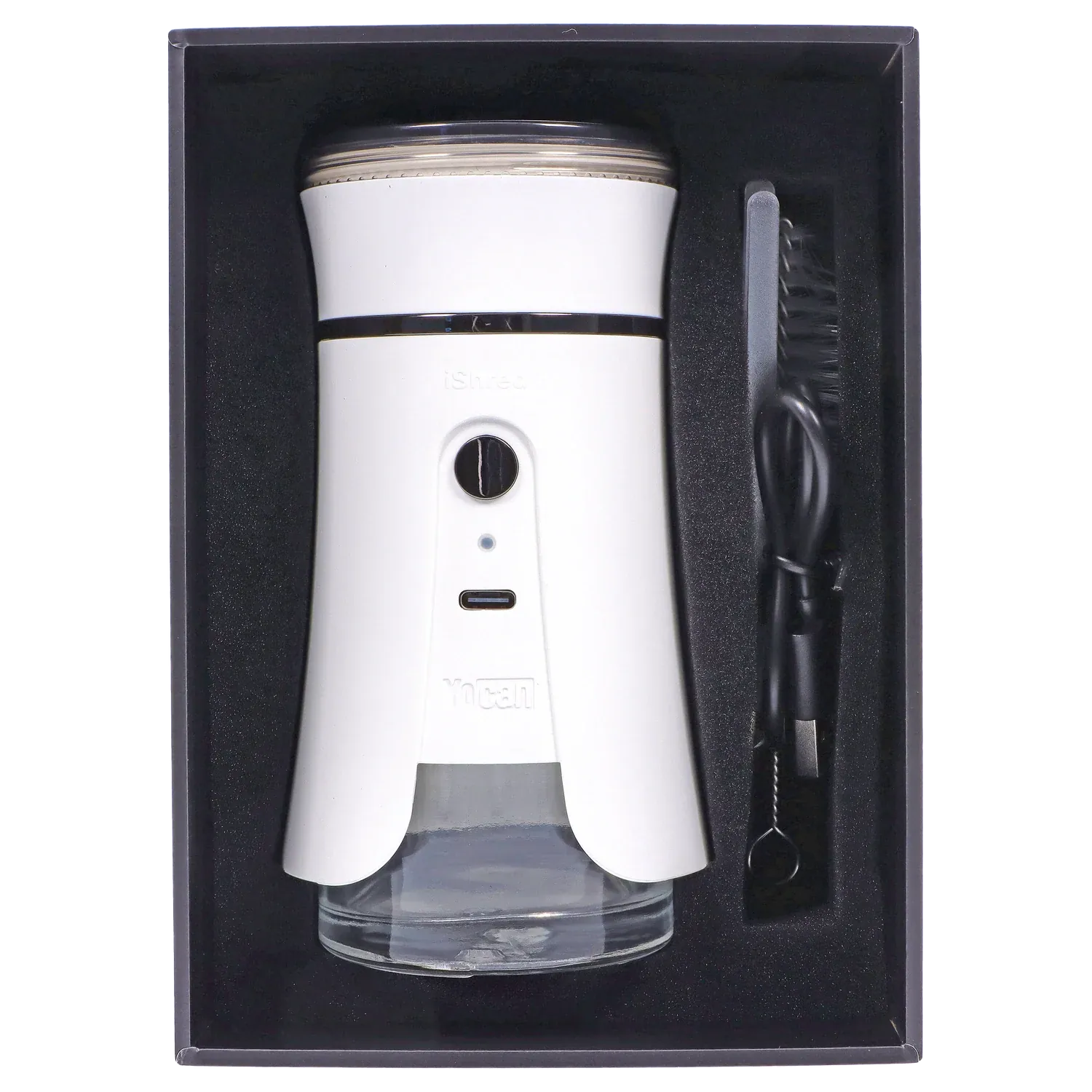 Top-down view of the ivory Yocan iShred Electronic Grinder nestled in black foam with its clear collection jar and cleaning brush to the right