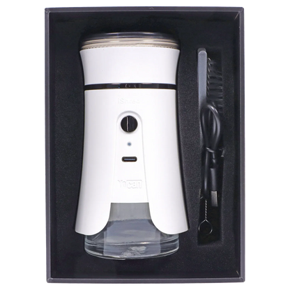 Top-down view of the ivory Yocan iShred Electronic Grinder nestled in black foam with its clear collection jar and cleaning brush to the right