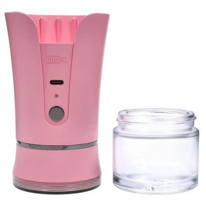 Close-up front view of the pink Yocan iShred Electronic Grinder showing its curved top, central button and USB port beside a clear detachable glass jar.