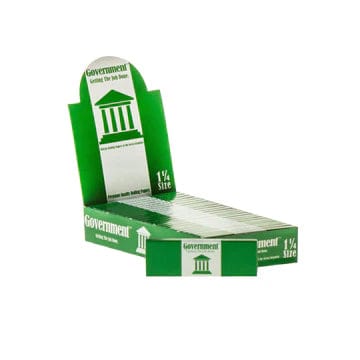 Angled three-quarter view of a green display box of Government 100% Wood Fibre Rolling Papers - 1 ¼ with stacked packs visible against a white background
