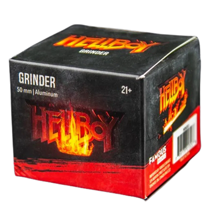 Angled close-up of the black and red Hellboy Inferno 3-Stufen Grinder - 50mm box showing flaming logo and "GRINDER 50 mm | Aluminium" text.