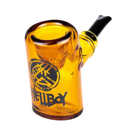 Close-up three-quarter view of the yellow Hellboy Sherlock Pfeife - Gelb glass pipe showing its rounded bowl, black mouthpiece and black Hellboy logo on the front.