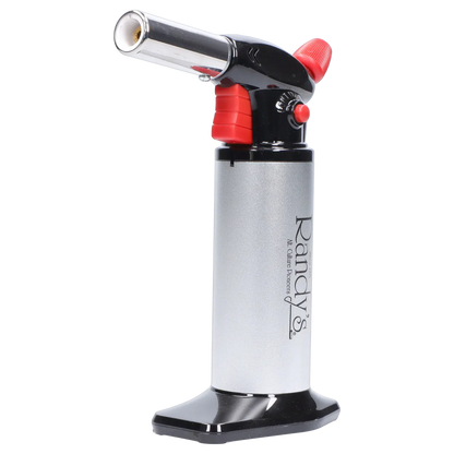 Close-up side view of Randy's Fahrenheit Butane Torch - Silver showing its angled chrome nozzle, red trigger and adjustment knob, and vertical silver body on a black base.