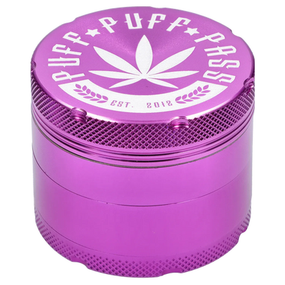 Close-up angled view of the purple Puff Puff Pass Aluminum Grinder 4pc -Purple-50mm showing the textured grip, white leaf logo and stamped lettering on the top.