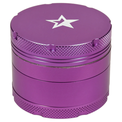 Close-up, slightly angled top view of the Famous X 4 pc Grinder -Purple - 50mm showing its purple metal finish, engraved star on the lid, and textured grip edges.