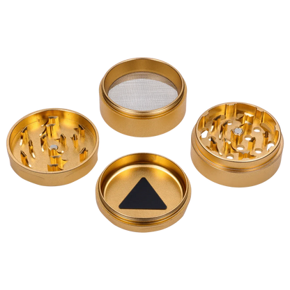 Top-down view of the disassembled Puff Puff Pass Strains GG4 Grinder-Champagne Gold showing four shiny gold compartments on white.