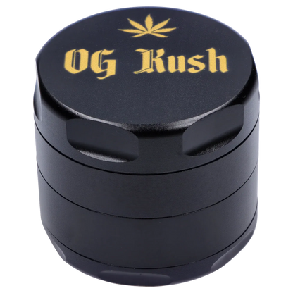 Angled close-up of the black Puff Puff Pass Strains OG Kush Grinder-Black showing its textured lid with gold "OG Kush" lettering and a small leaf motif.