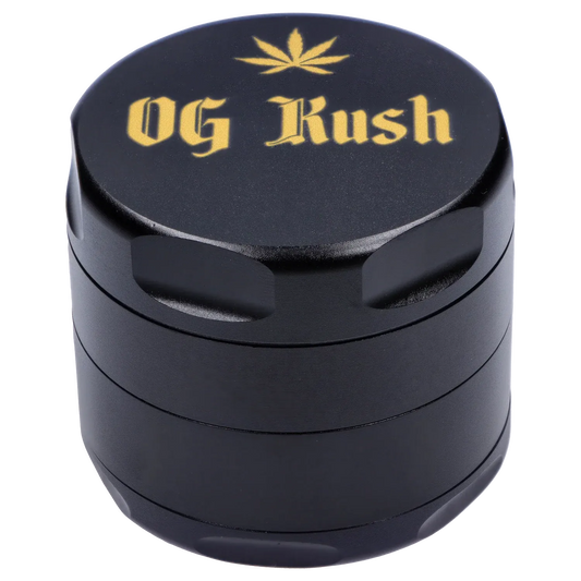 Angled close-up of the black Puff Puff Pass Strains OG Kush Grinder-Black showing its textured lid with gold "OG Kush" lettering and a small leaf motif.