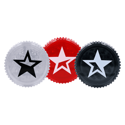 Close-up of three Famous X Acrylic Grinder-59mm tops in a row showing clear, red, and black star-emblazoned lids against a black background