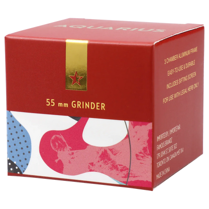 Angled close-up of the red box packaging for Famous Design Aquarius Aluminum 4 pc Grinder - Aqua, showing gold text and a patterned lower panel.