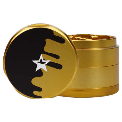 Close-up three-quarter view of the gold Famous Design Surrender Aluminum 4 pc Grinder with its black star-topped lid slightly ajar.