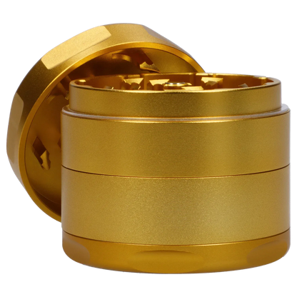 Close-up angled view of the gold Famous Design Surrender Aluminum 4 pc Grinder showing its textured stacked chambers and exposed teeth.