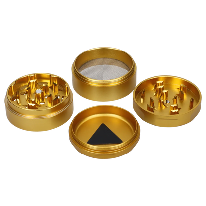 Top-down view of the disassembled Famous Design Surrender Aluminum 4 pc Grinder - Gold showing four gold metal sections with tooth-like teeth and a mesh screen.