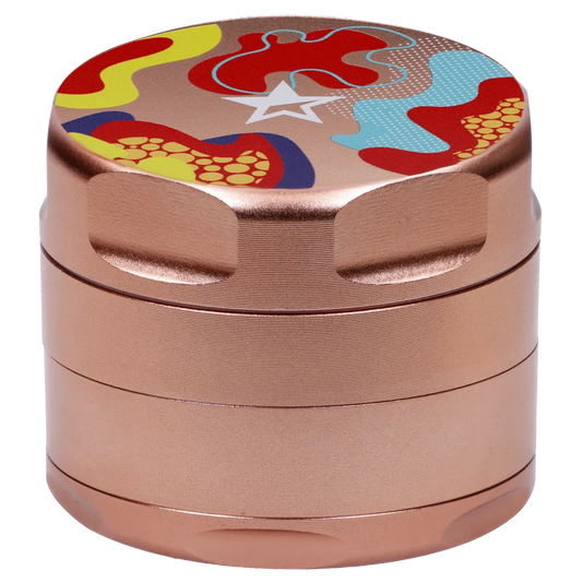 Close-up angled view of the Famous Design Papaya Aluminum 4pc Grinder - Rose Gold showing its textured rose-gold metal body and colorful abstract patterned top.