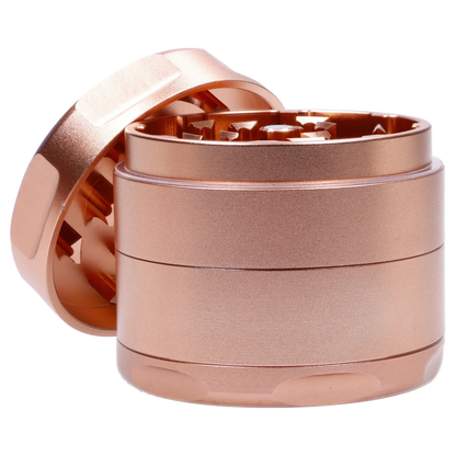 Close-up angled view of the Famous Design Papaya Aluminum 4pc Grinder - Rose Gold showing its stacked cylindrical chambers and exposed serrated teeth.