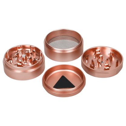 Top-down view of the four separated rose gold Famous Design Papaya Aluminum 4pc Grinder pieces showing two toothed halves, a mesh screen chamber, and a magnetic base.